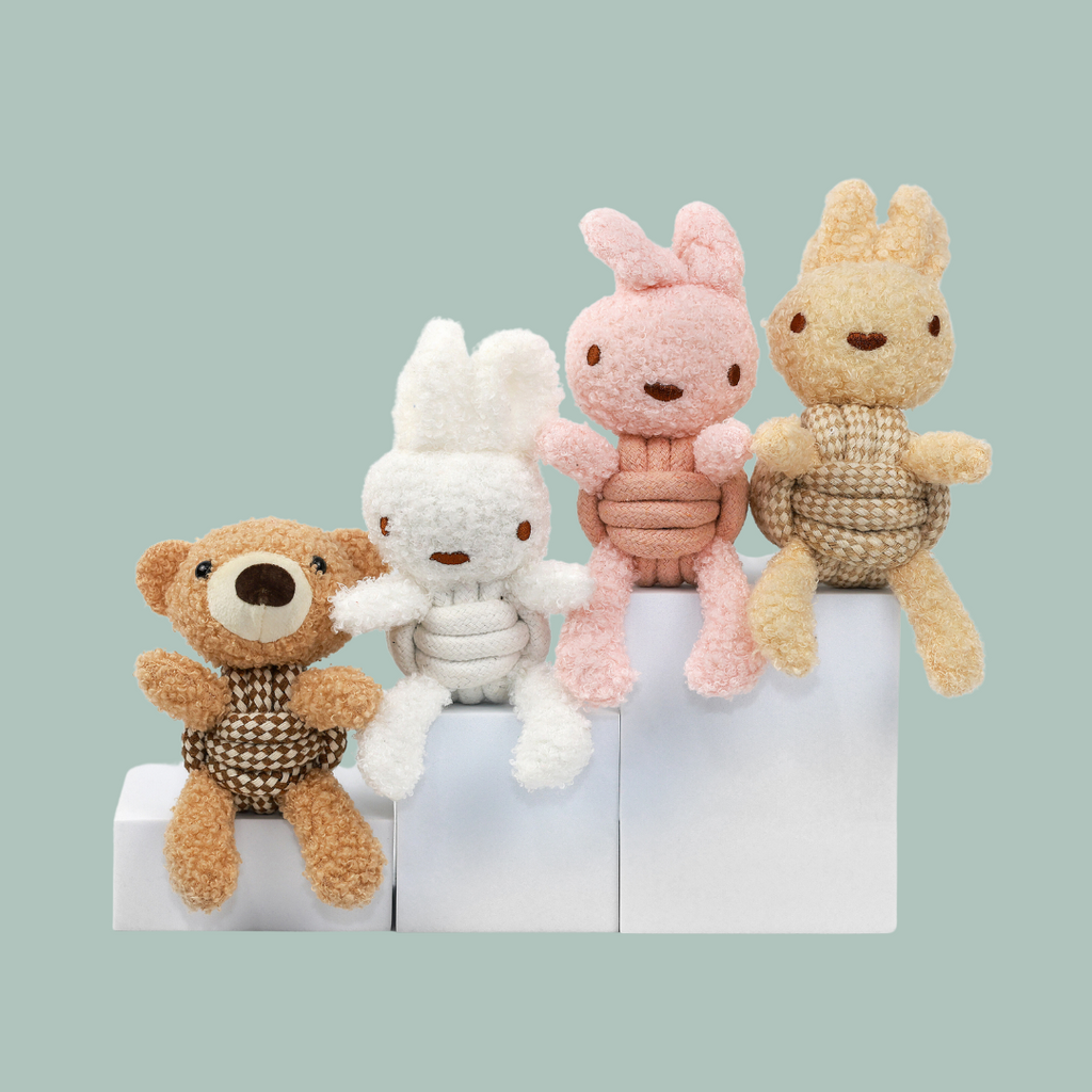 Four plush toys on a white block against a light green background